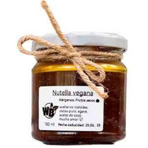 Un tarro de cristal con la etiqueta "Nutella vegana", tapa blanca y lazo de cordel, que contiene una pasta marrón para untar. En la etiqueta figuran los ingredientes y la fecha de caducidad.