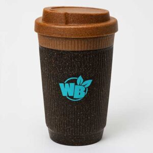 Taza de café reutilizable de color marrón con superficie texturizada, tapa marrón y logotipo "WB" azul con dos hojas verdes en la parte delantera, sobre un fondo blanco liso.
